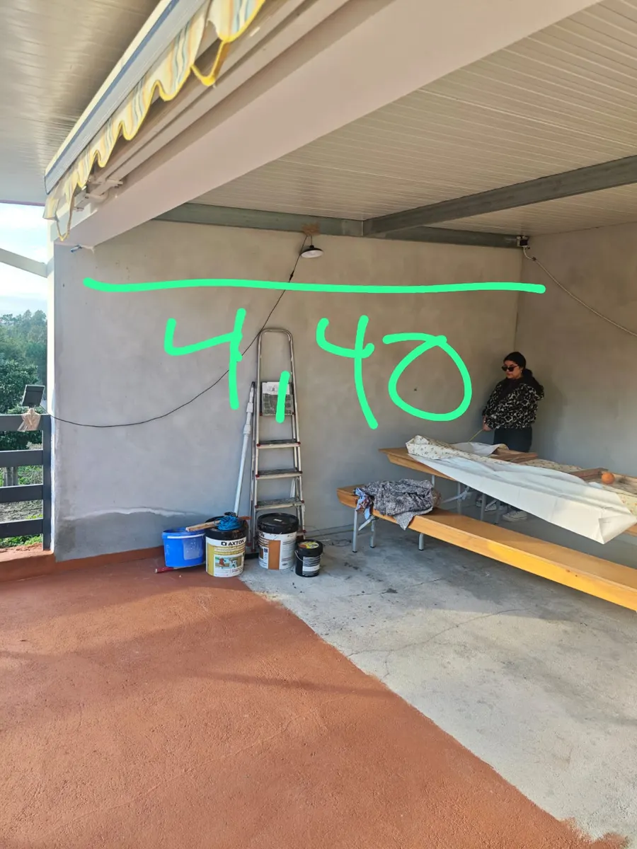 Vorher: graue verputzte Terrassenwand mit Leiter, Farbeimern und neonfarbenen Maßnotizen aus der Aufmaßphase