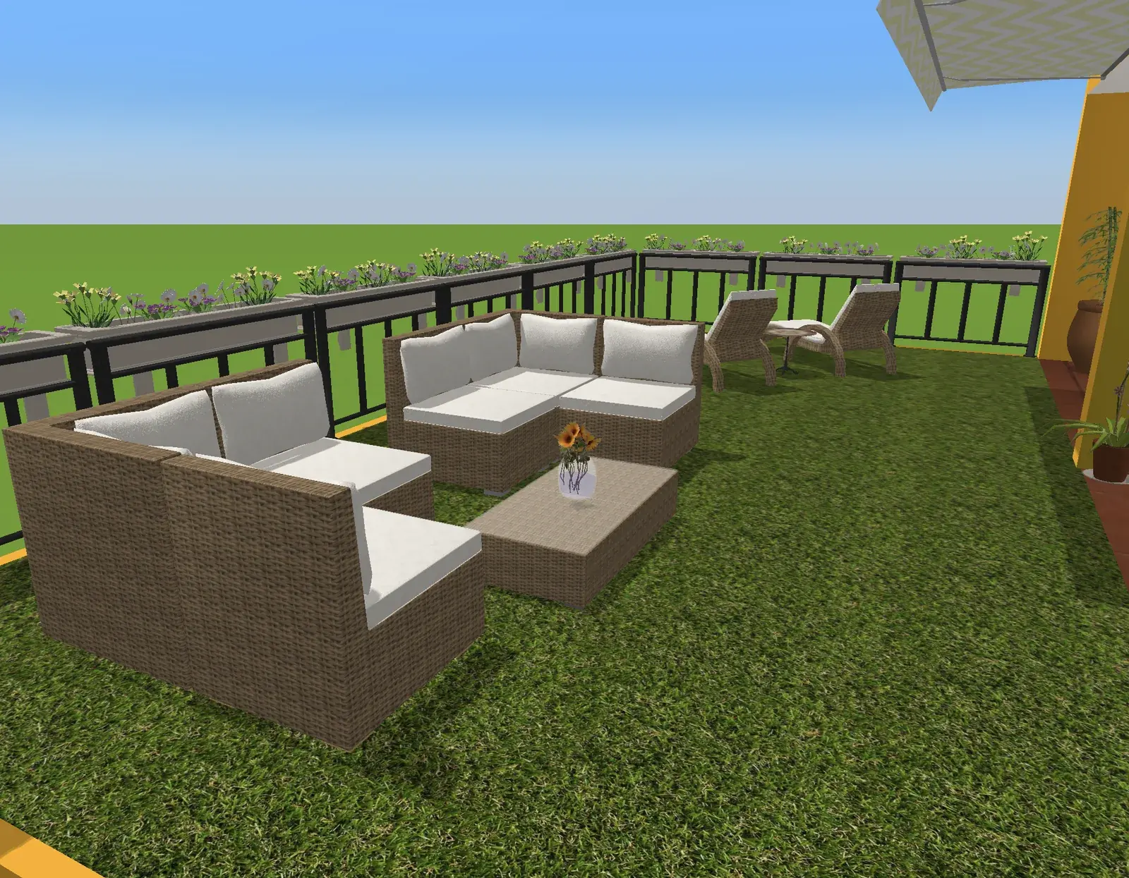 Rattan-Loungegruppe mit weißen Kissen um einen niedrigen Rattan-Couchtisch auf Kunstrasen, dahinter zwei Sonnenliegen und Geländerkästen voller gelber, weißer und violetter Blumen