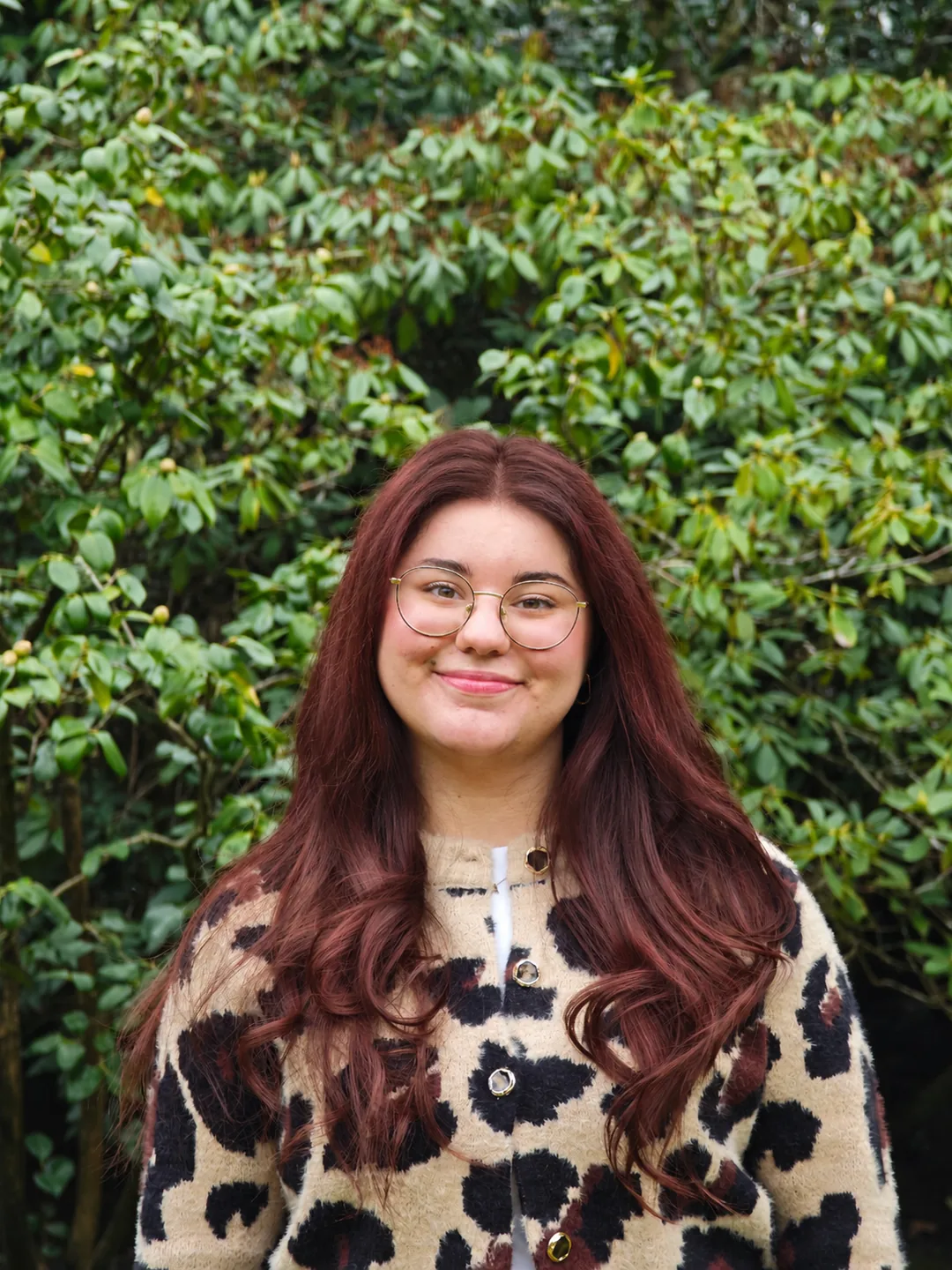 Dania Lima, Gründerin von Daradiant Interiors, vor einer grünen Hecke